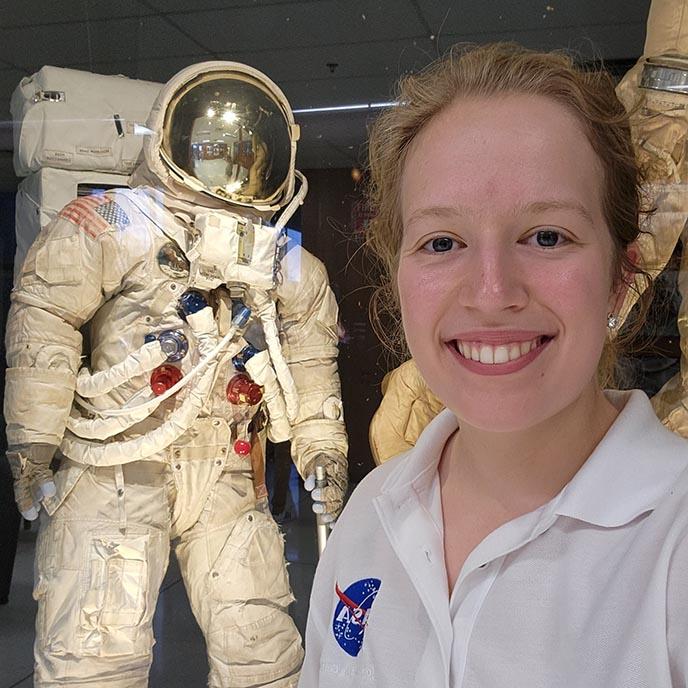 莎拉·斯图尔特 poses with a NASA spacesuit .